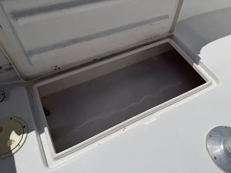 Slide: The Image of An open storage compartment on a boat with a white deck and metal fittings. - 31
