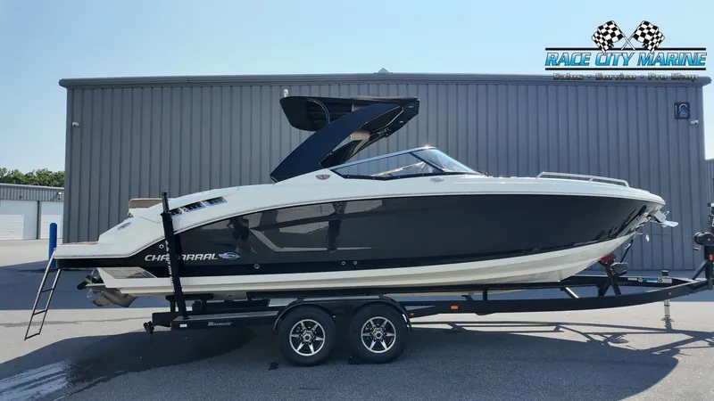 The Image of A 2015 Chaparral 277 SSX boat on a trailer in front of a gray building. - 1