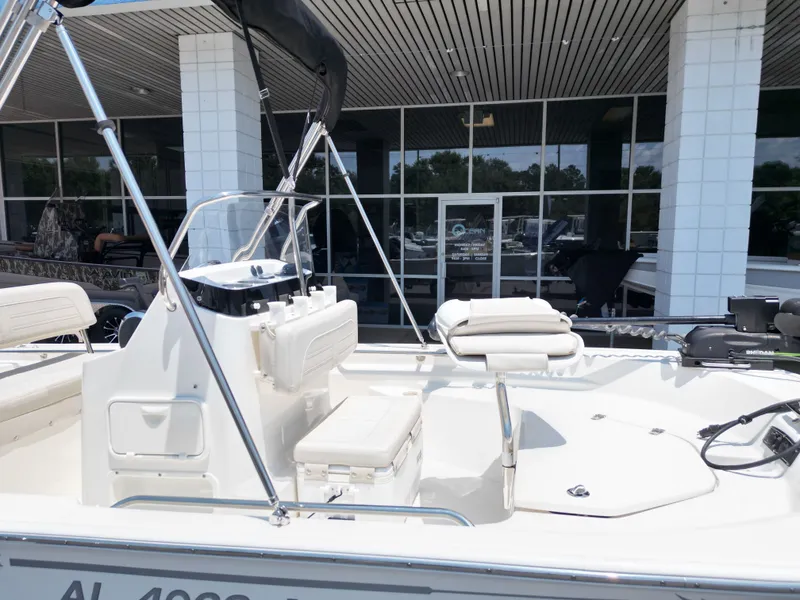 Slide: The Image of A 2023 Boston Whaler 150 Montauk with a white hull and seating, parked in front of a building. - 22