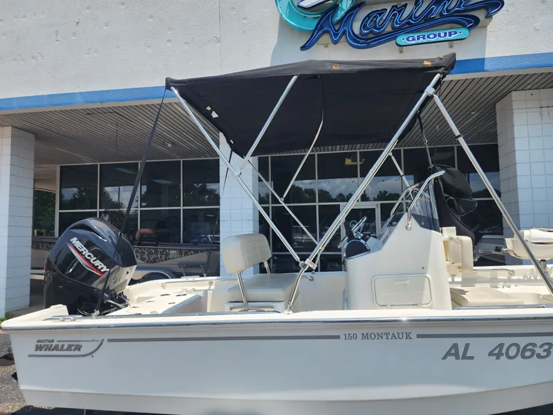 Slide: The Image of A 2023 Boston Whaler 150 Montauk with a black sunshade, parked in front of a building. - 10