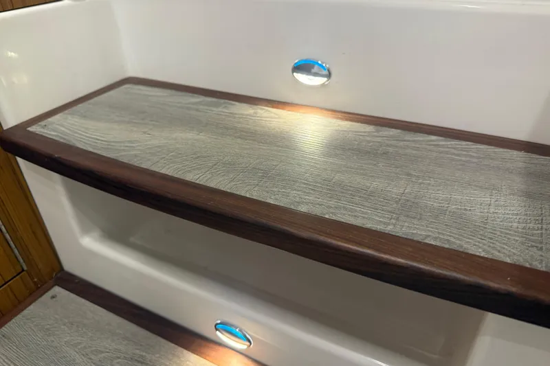 Slide: The Image of 2024 Solace 30HCS boat interior step with wood finish and LED lighting. - 26