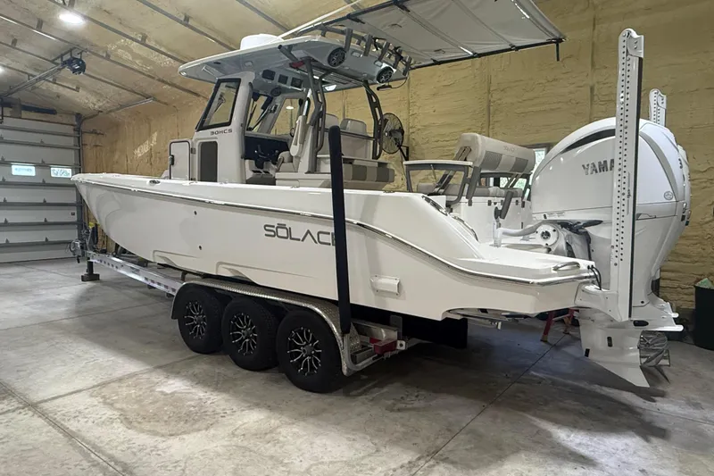 Slide: The Image of 2024 Solace 30HCS boat in garage, featuring Yamaha engines and sleek design on a trailer. - 2