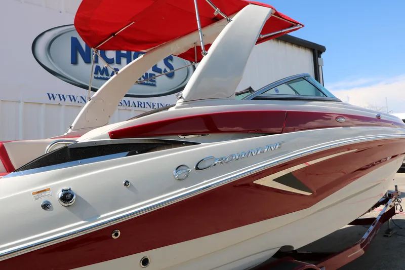 Slide: The Image of 2022 Crownline Eclipse E255 boat with red and white design, displayed outdoors. - 11