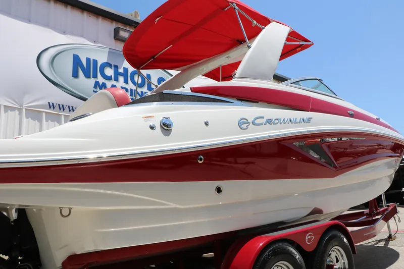 Slide: The Image of 2022 Crownline Eclipse E255 boat with red and white design, displayed at a marine dealership. - 4