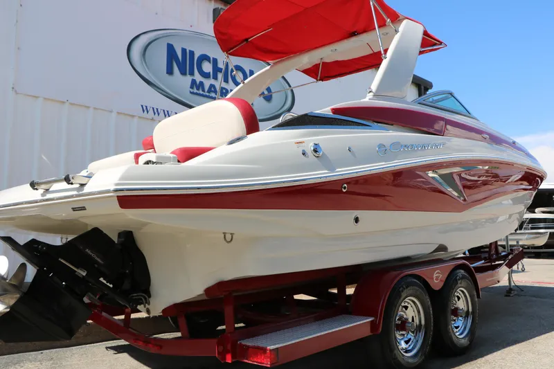 Slide: The Image of 2022 Crownline Eclipse E255 boat with red accents on a trailer, displayed outdoors. - 4
