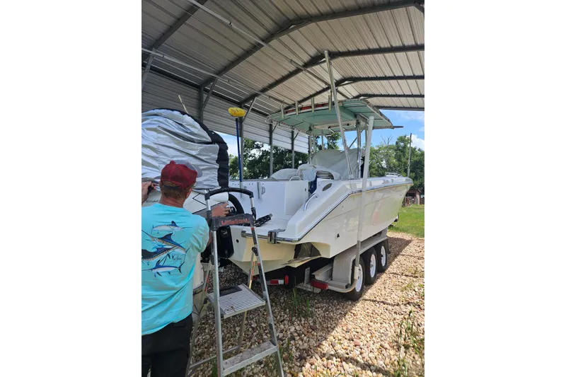 Slide: The Image of 2003 Dakota 36 CC boat under shelter, man working on ladder nearby. - 29