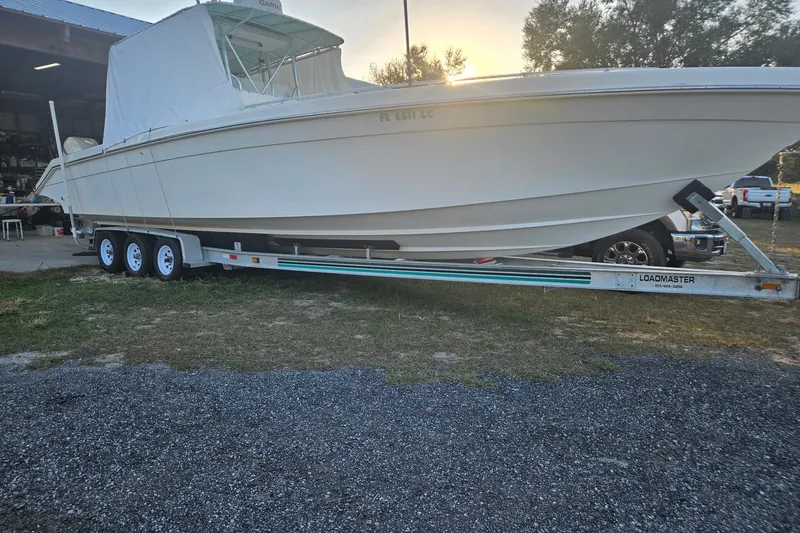 Slide: The Image of 2003 Dakota 36 CC boat on Loadmaster trailer, parked outdoors near a garage. - 19