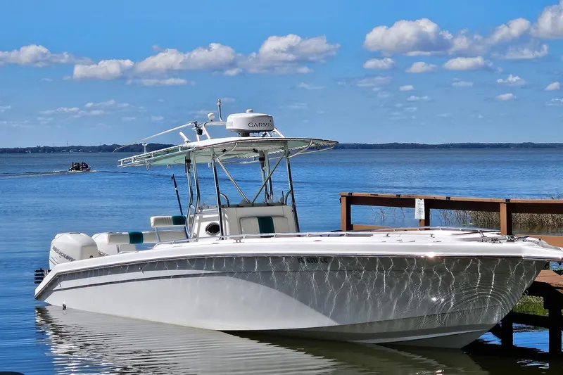 Slide: The Image of 2003 Dakota 36 CC boat docked on a sunny day by a calm lake. - 2