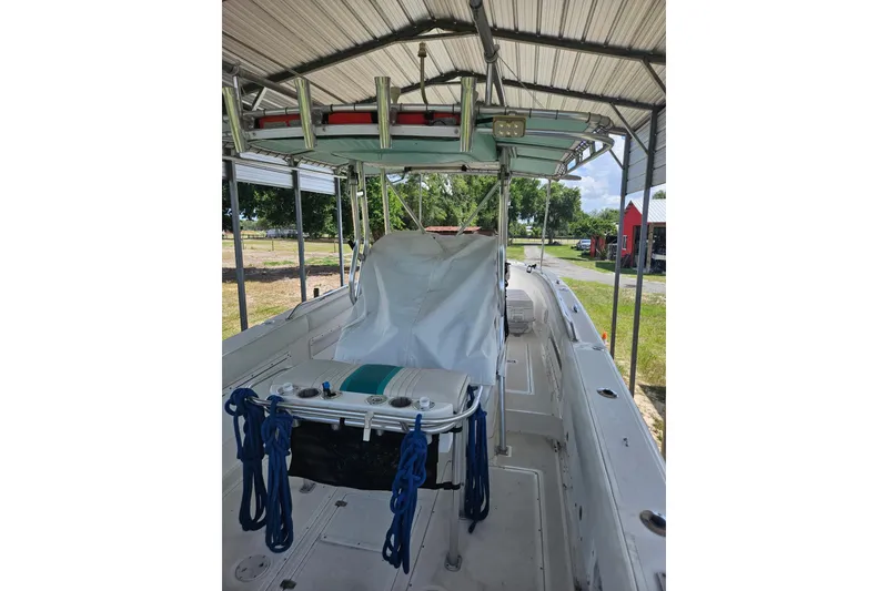 Slide: The Image of 2003 Dakota 36 CC boat under a metal canopy, featuring a covered console and blue ropes. - 30