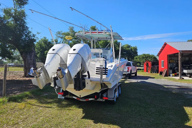 Slide: The Image of 2003 Dakota 36 CC boat with dual engines on a trailer near a red barn. - 26