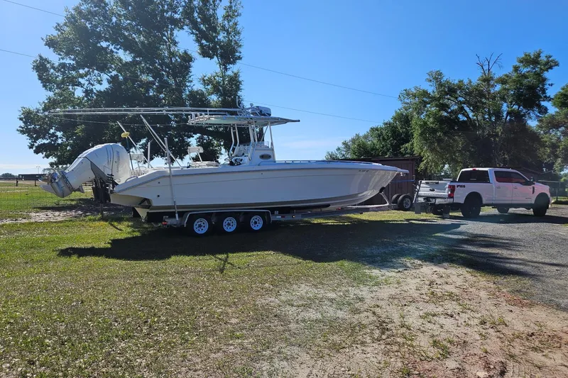 Slide: The Image of 2003 Dakota 36 CC boat on trailer, hitched to a white truck, parked outdoors. - 4