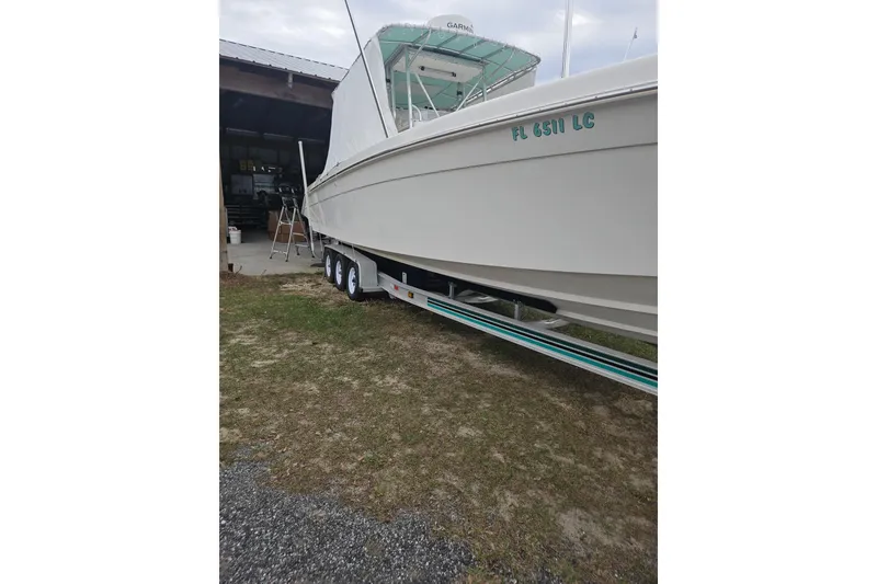 Slide: The Image of 2003 Dakota 36 CC boat on trailer, parked near a garage. - 15