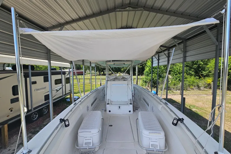 Slide: The Image of 2003 Dakota 36 CC boat under canopy, featuring spacious deck and seating. - 12