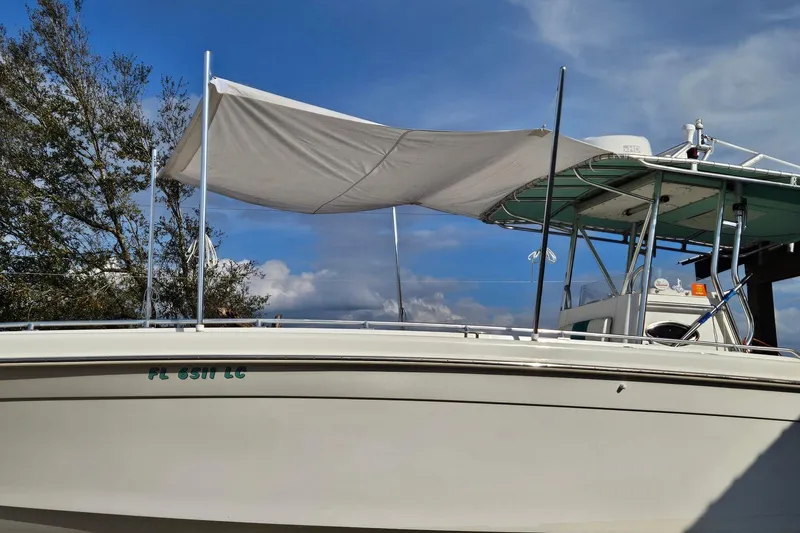 Slide: The Image of 2003 Dakota 36 CC boat with canopy, parked outdoors under a clear blue sky. - 22