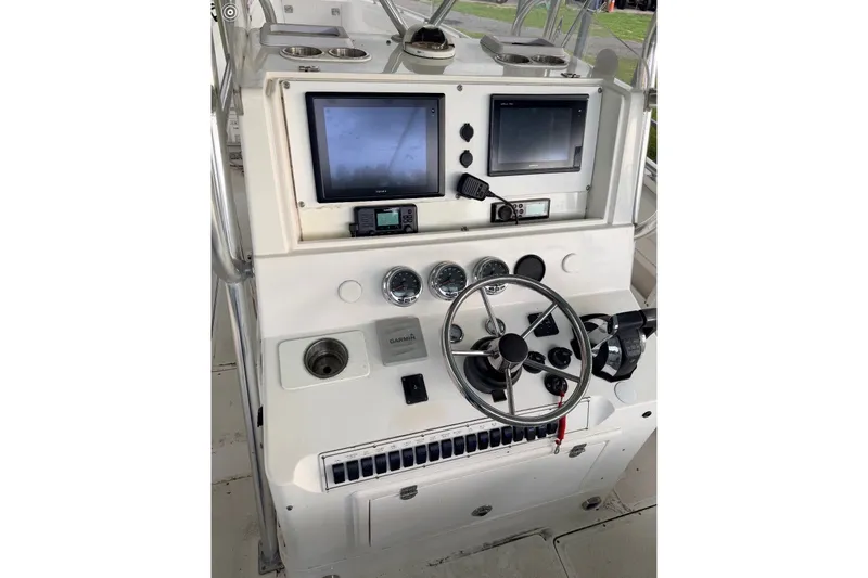 Slide: The Image of Control panel of a 1998 Dakota 36 CC boat with steering wheel and navigation screens. - 39