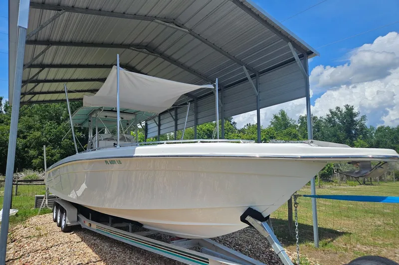 Slide: The Image of 2003 Dakota 36 CC boat under metal canopy, parked on trailer in sunny outdoor setting. - 37