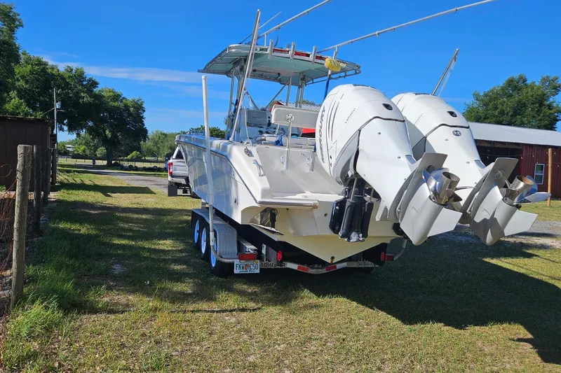 Slide: The Image of 2003 Dakota 36 CC boat with dual outboard motors on a trailer, parked outdoors. - 28