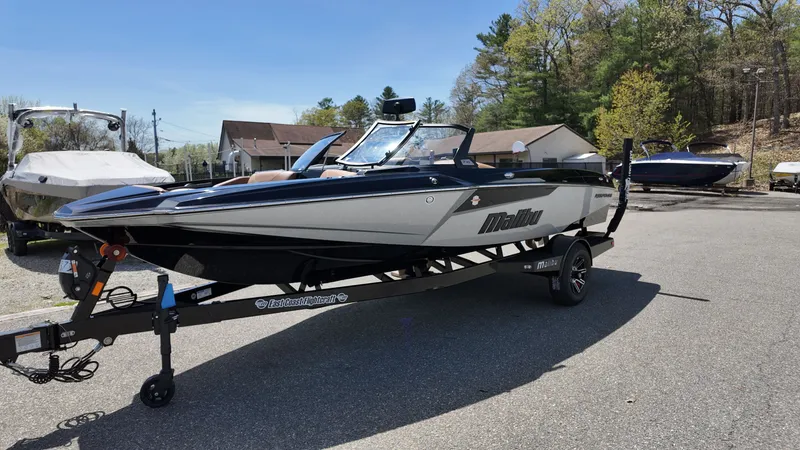Slide: The Image of A sleek 2025 Malibu TXi boat on a trailer in a sunny outdoor setting. - 3