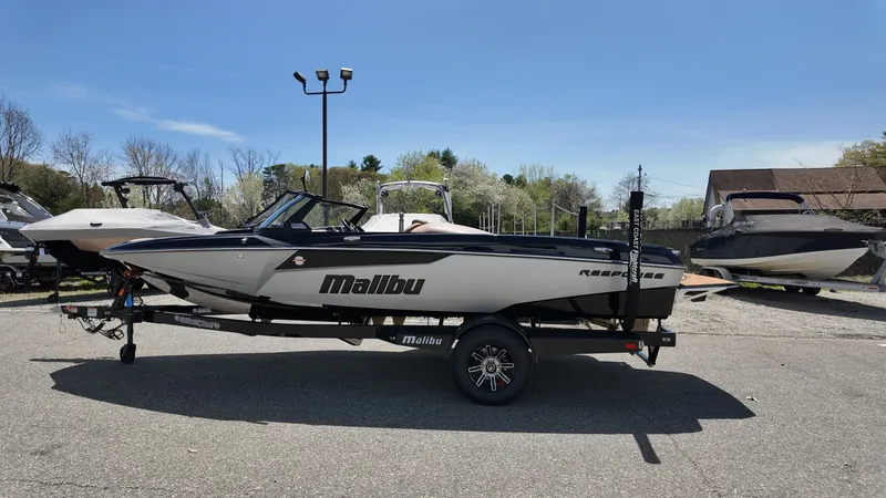 Slide: The Image of A 2025 Malibu TXi boat is on a trailer in an outdoor area. - 4