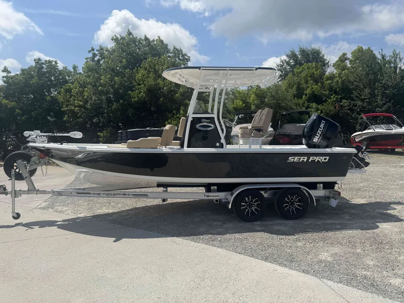 The Image of A 2027 Sea Pro 230 DLX boat on a trailer, featuring an outboard motor and T-top. - 1