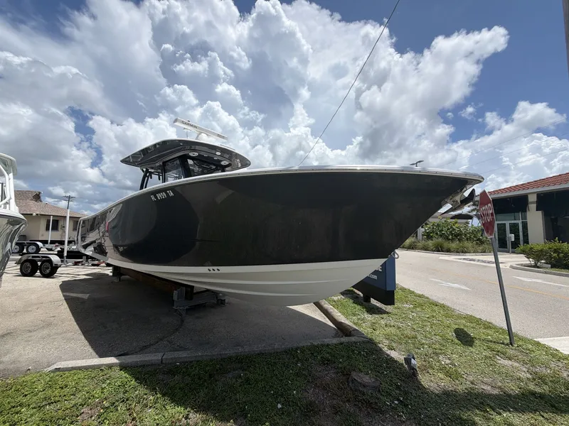 Slide: The Image of A black 2021 Sportsman Open 322 Center Console boat on a trailer under a cloudy sky. - 3