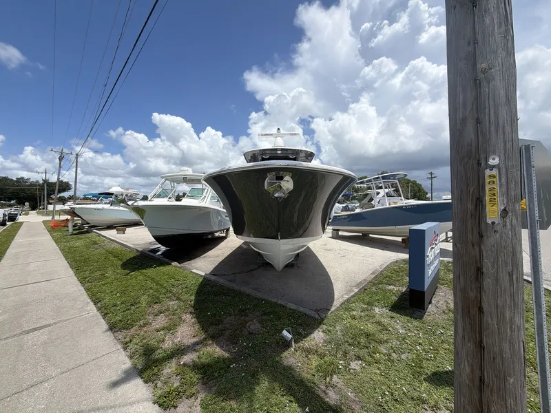 Slide: The Image of A 2021 Sportsman Open 322 Center Console boat is parked alongside other boats on a lot. - 2