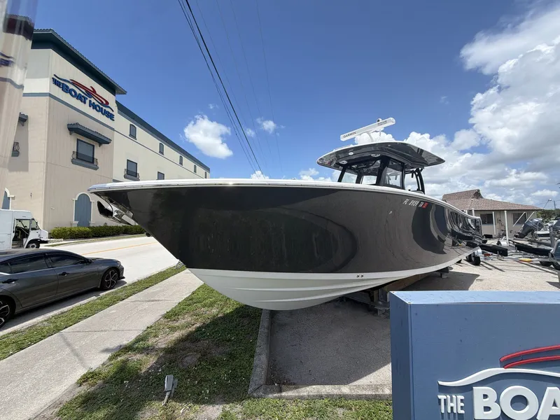 The Image of A 2021 Sportsman Open 322 Center Console boat on a trailer in front of a building. - 1