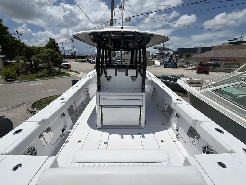 Slide: The Image of The image shows a 2021 Sportsman Open 322 Center Console boat. It features a spacious white deck with a central helm and multiple seating areas. The sky is cloudy. - 22