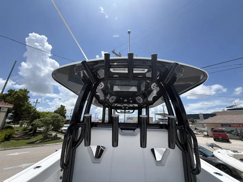 Slide: The Image of The image shows the helm of a 2021 Sportsman Open 322 Center Console boat with rod holders. - 12
