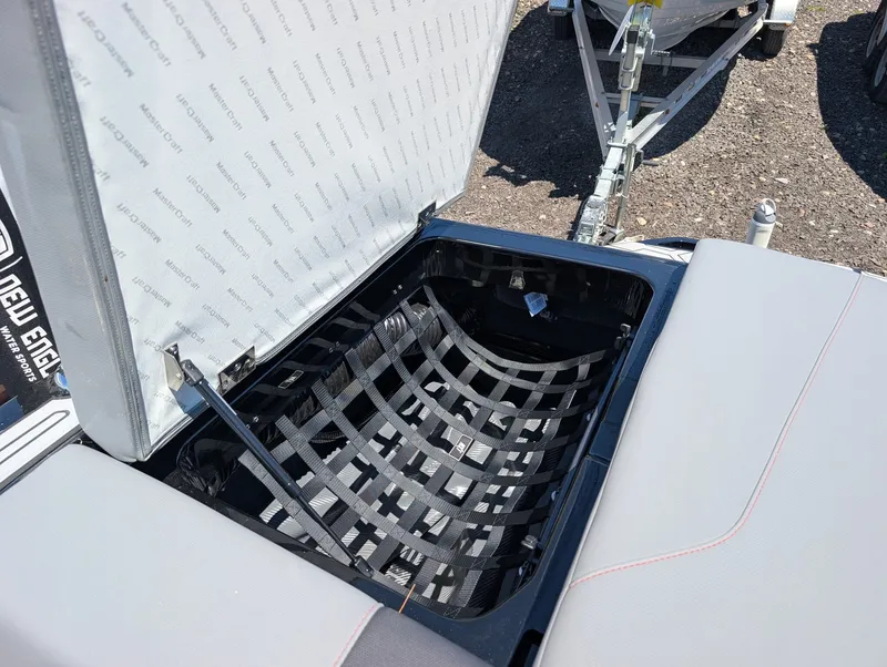 Slide: The Image of An open storage compartment on a MasterCraft NXT 23 boat reveals a net for securing items. - 16