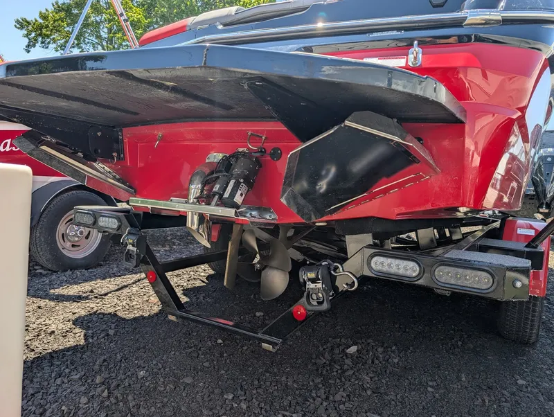 Slide: The Image of The image shows the rear of a red 2025 MasterCraft NXT 23 boat with visible propeller and trailer. - 3