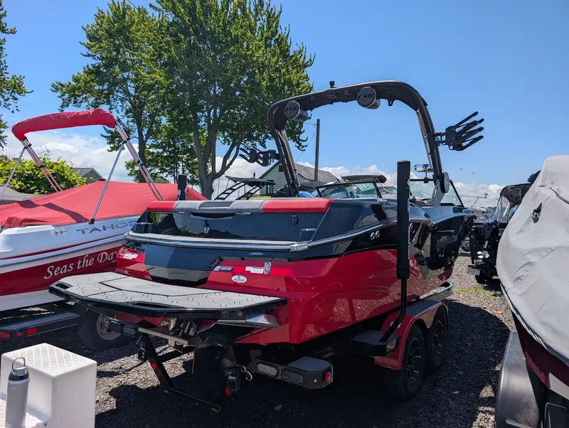 Slide: The Image of A red 2025 MasterCraft NXT 23 boat on a trailer, surrounded by other boats. - 2