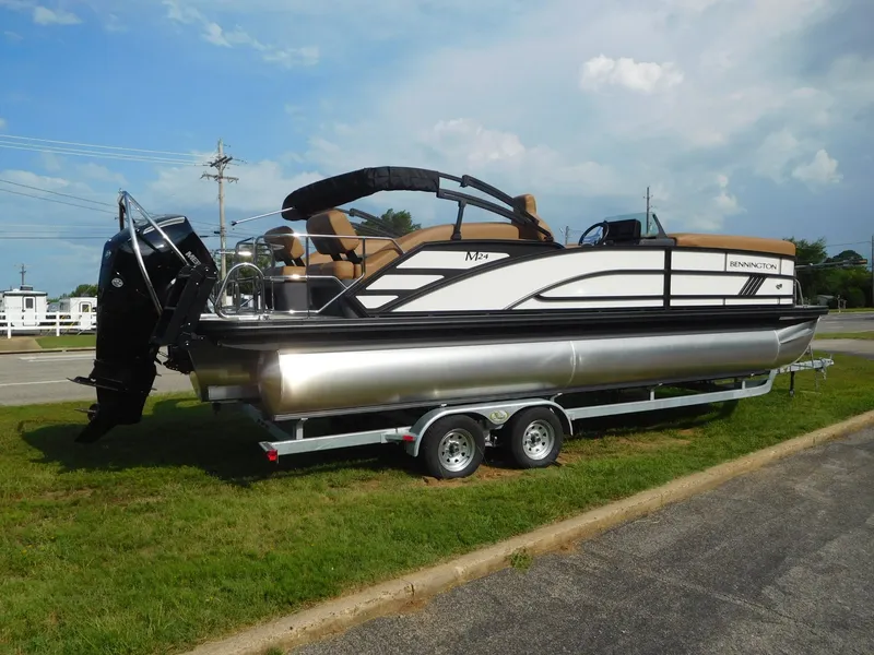 Slide: The Image of A 2026 Bennington 24 MSL pontoon boat on a trailer, set on a grassy area. - 5