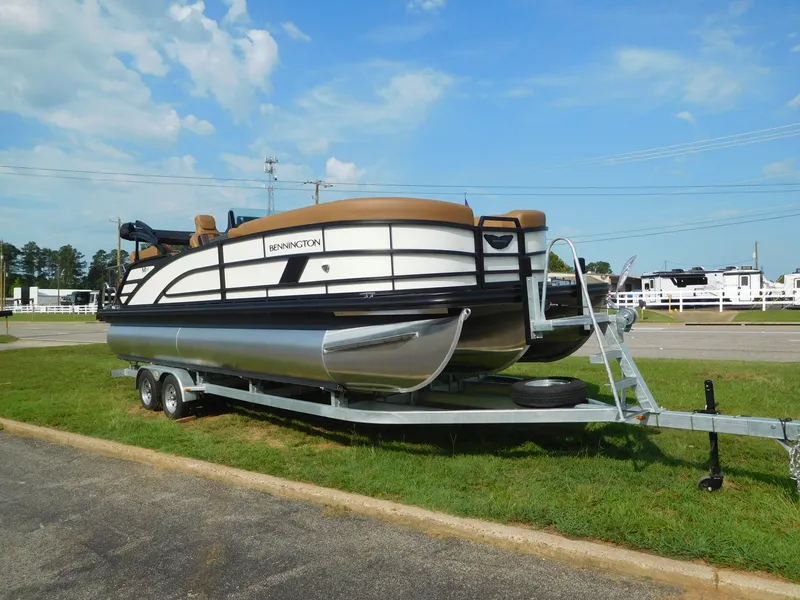 Slide: The Image of A 2026 Bennington 24 MSL pontoon boat on a trailer, parked on grass. - 6