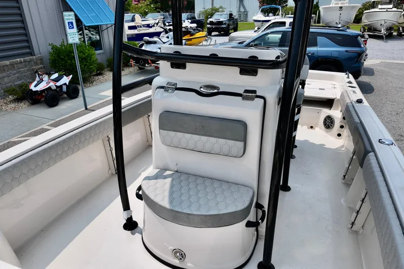 Slide: The Image of 2027 Carolina Skiff 21 Ultra Elite boat interior with seating and storage, parked outdoors. - 8