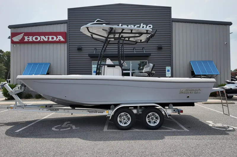 Slide: The Image of 2027 Carolina Skiff 21 Ultra Elite boat on trailer, parked outside a Honda dealership. - 1