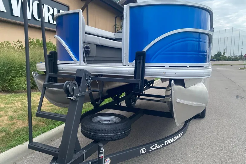 Slide: The Image of 2026 Sun Tracker Party Barge 18 DLX pontoon boat on trailer, blue exterior. - 2