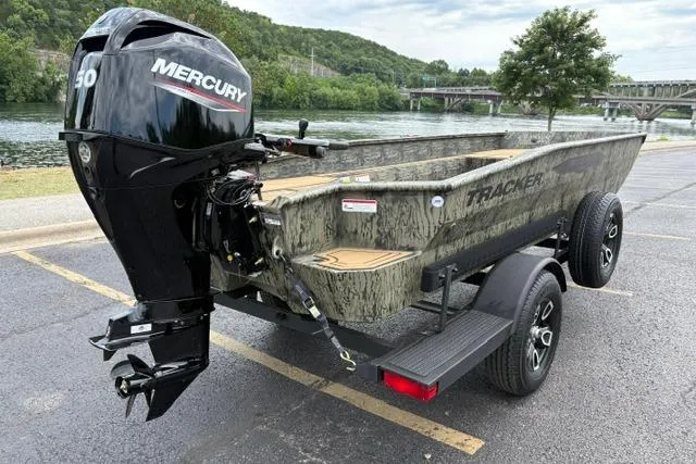 Slide: The Image of 2026 Tracker Grizzly 1650 T Prairie Wings Edition boat with Mercury engine, parked near a river. - 9