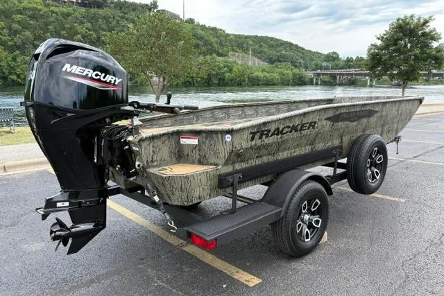 Slide: The Image of 2026 Tracker Grizzly 1650 T Prairie Wings Edition boat with Mercury engine, parked near a river. - 8