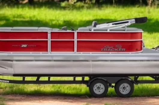 The Image of 2026 Sun Tracker Party Barge 20 DLX pontoon boat on trailer, red and silver design. - 0