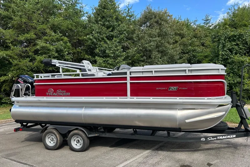 The Image of 2026 Sun Tracker SportFish 20 DLX pontoon boat on trailer, parked outdoors. - 0