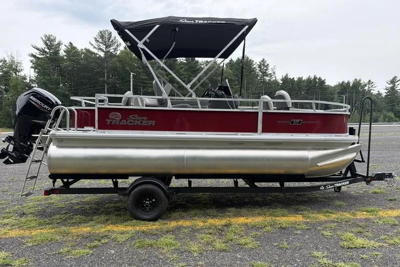 Slide: The Image of 2026 Sun Tracker Bass Buggy 18 DLX pontoon boat on trailer, parked outdoors. - 3