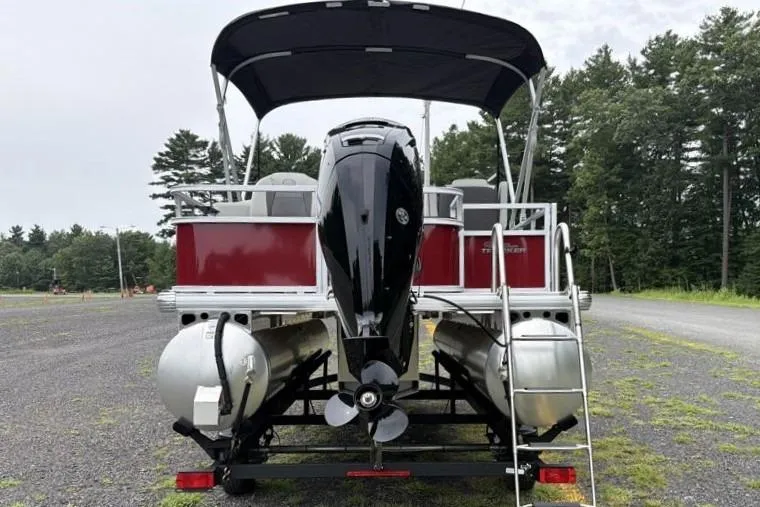 Slide: The Image of 2026 Sun Tracker Bass Buggy 18 DLX pontoon boat, rear view, parked outdoors. - 10