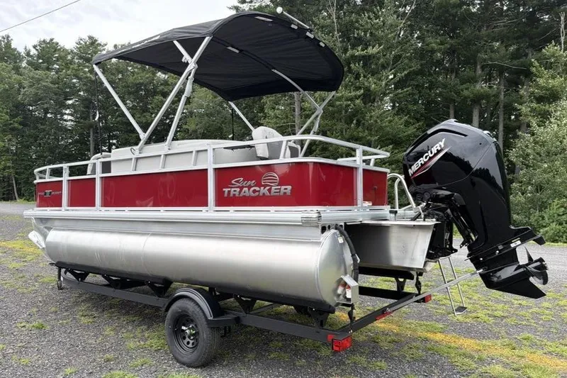 Slide: The Image of 2026 Sun Tracker Bass Buggy 18 DLX pontoon boat with Mercury outboard motor, parked outdoors. - 4