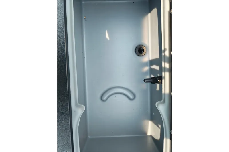 Slide: The Image of Livewell compartment of 2026 Sun Tracker SportFish 20 DLX boat, featuring drain and handle. - 24