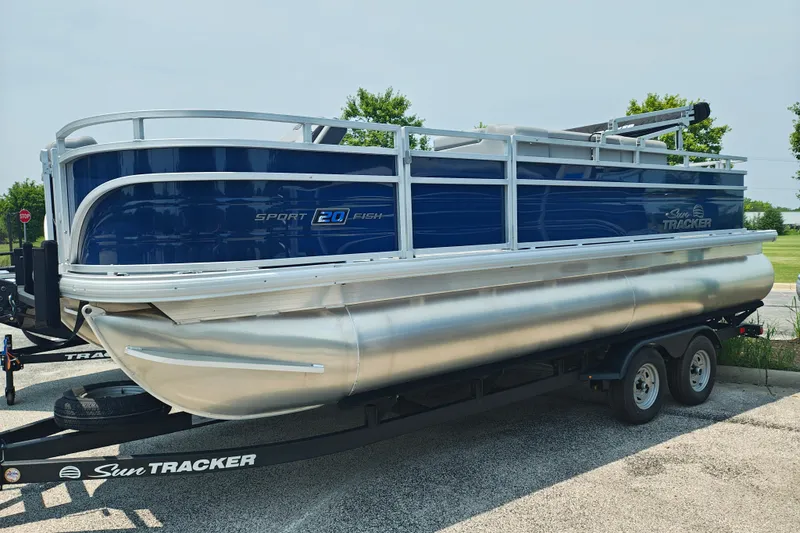 The Image of 2026 Sun Tracker SportFish 20 DLX pontoon boat on trailer, parked outdoors. - 1
