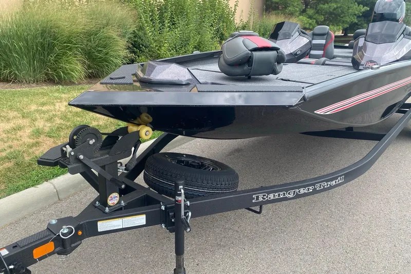 Slide: The Image of 2026 Ranger RT198P boat on trailer, parked on pavement with greenery background. - 1
