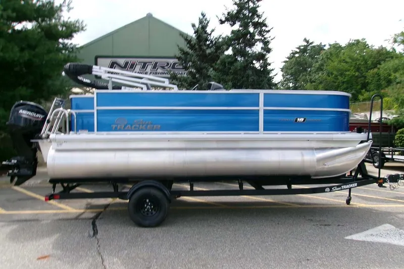 The Image of 2026 Sun Tracker Party Barge 18 DLX pontoon boat on trailer, parked outdoors. - 0