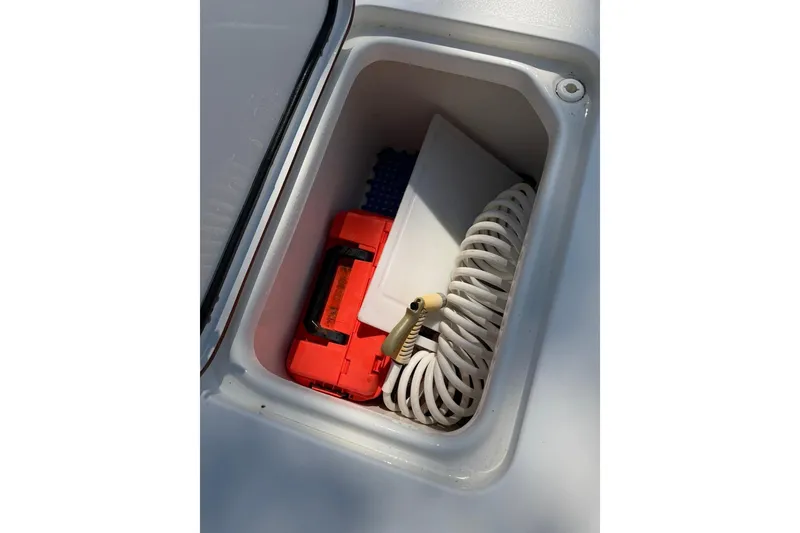 Slide: The Image of Storage compartment on 2021 Sea Pro 248 Bay boat with coiled hose and red container. - 27