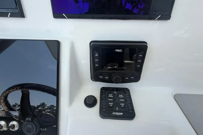 Slide: The Image of Control panel of a 2021 Sea Pro 248 Bay boat with audio system and trim tab controls. - 8